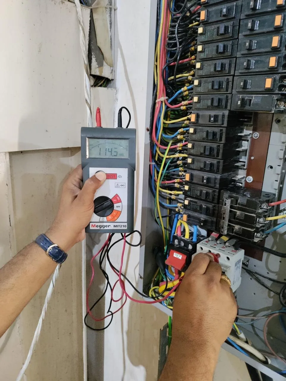 Technician testing a distribution board with an insulation tester