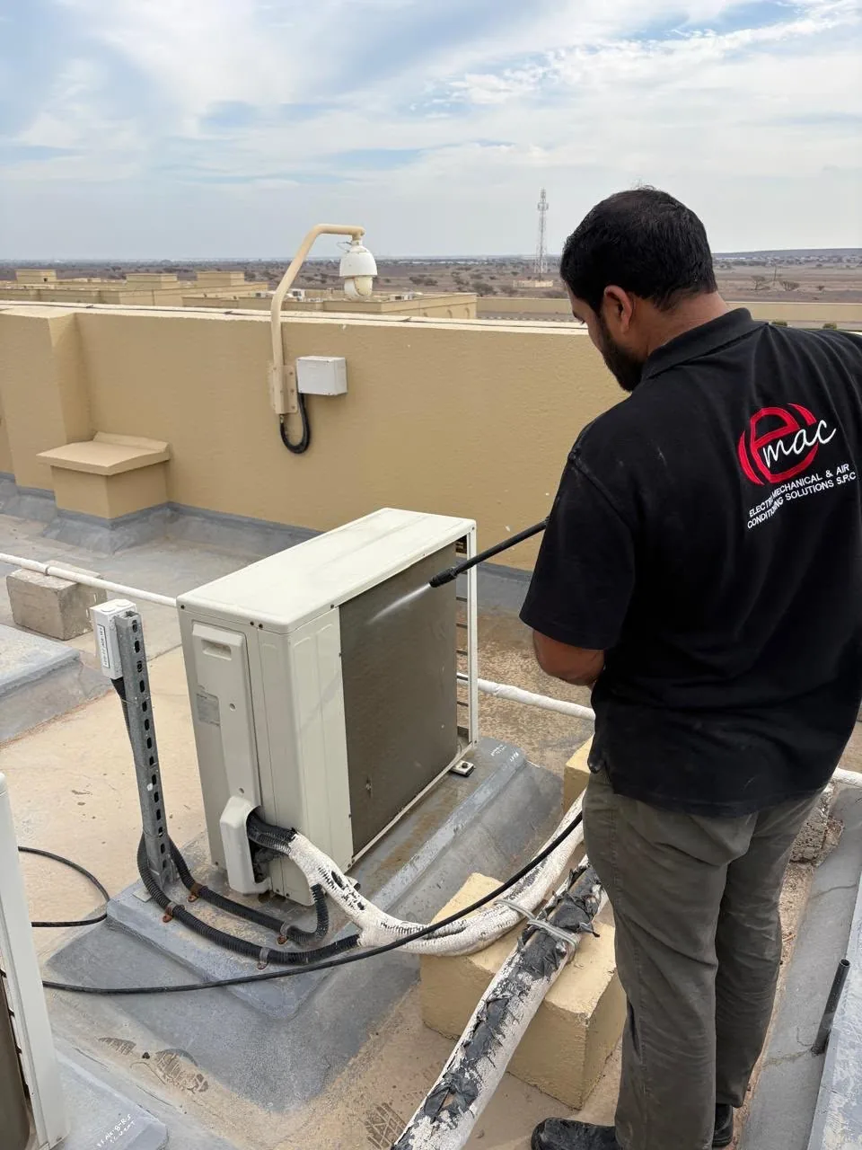EMACS technician servicing a rooftop air-conditioning unit