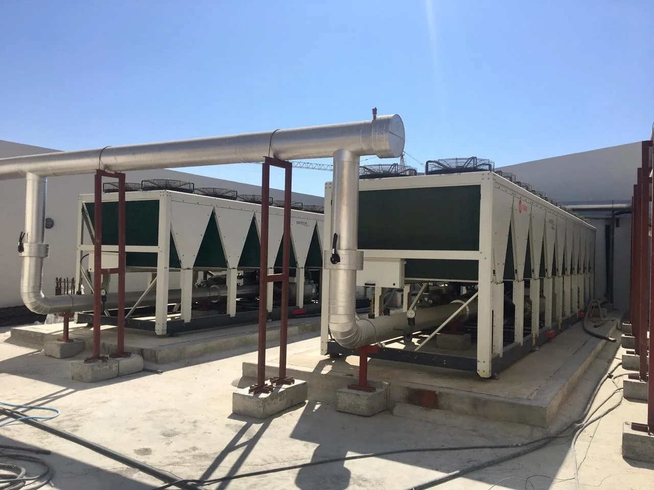 Air-cooled chillers and insulated chilled water pipework on a roof
