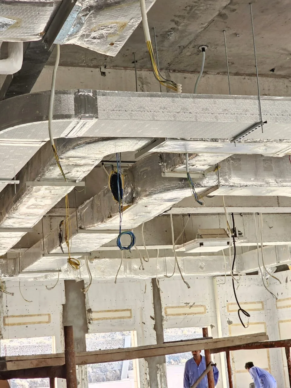 Ductwork installation in progress in an open ceiling
