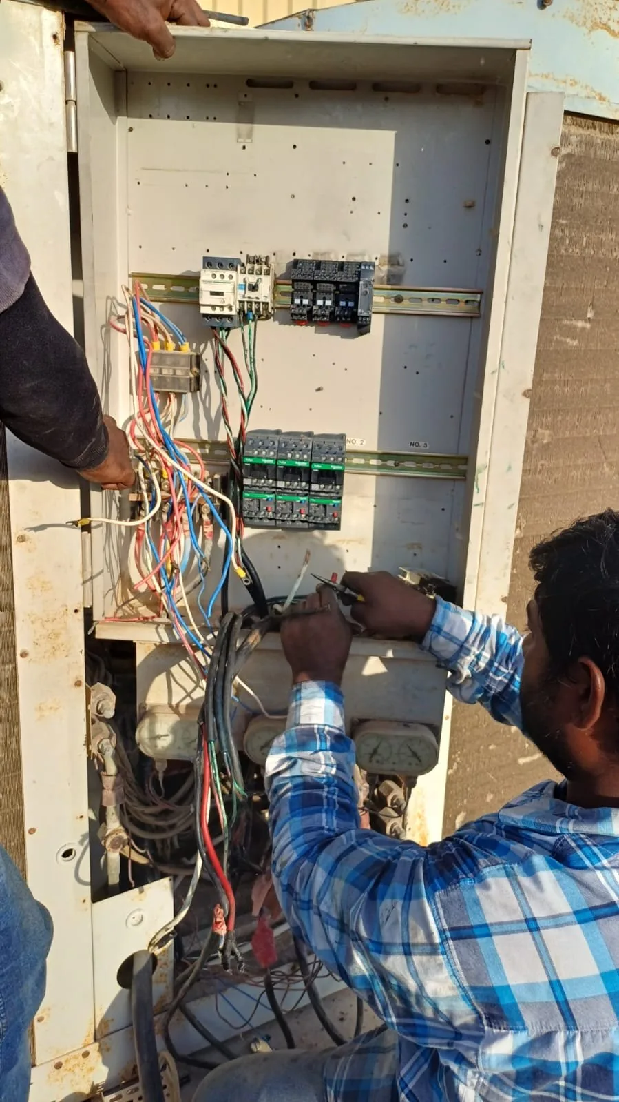 Technician wiring the control panel of an outdoor unit