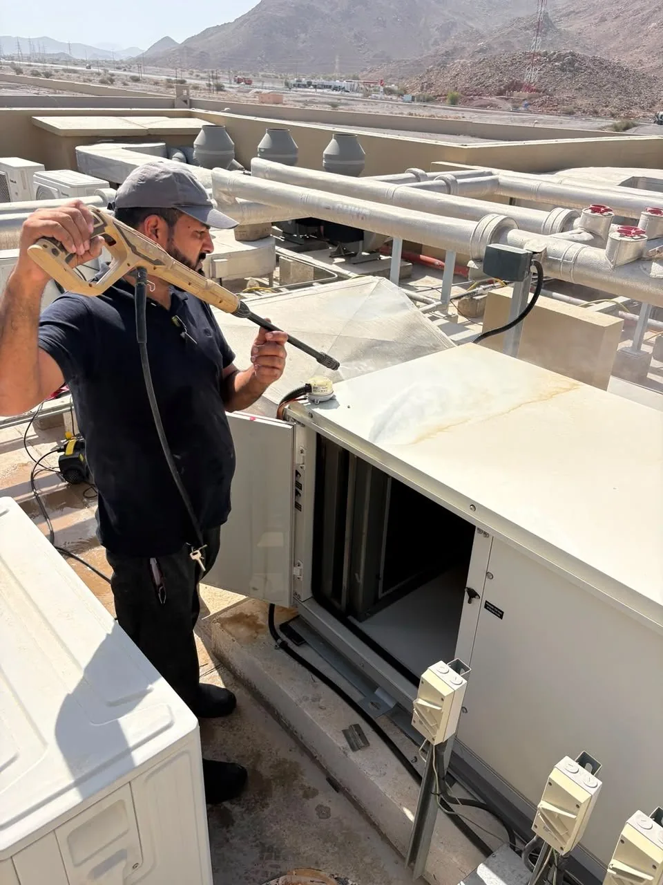 Technician servicing an open rooftop unit